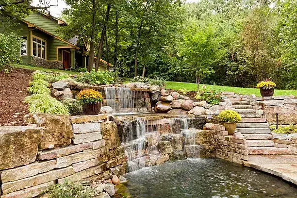 Multi-tiered stone waterfall with retaining wall and garden steps